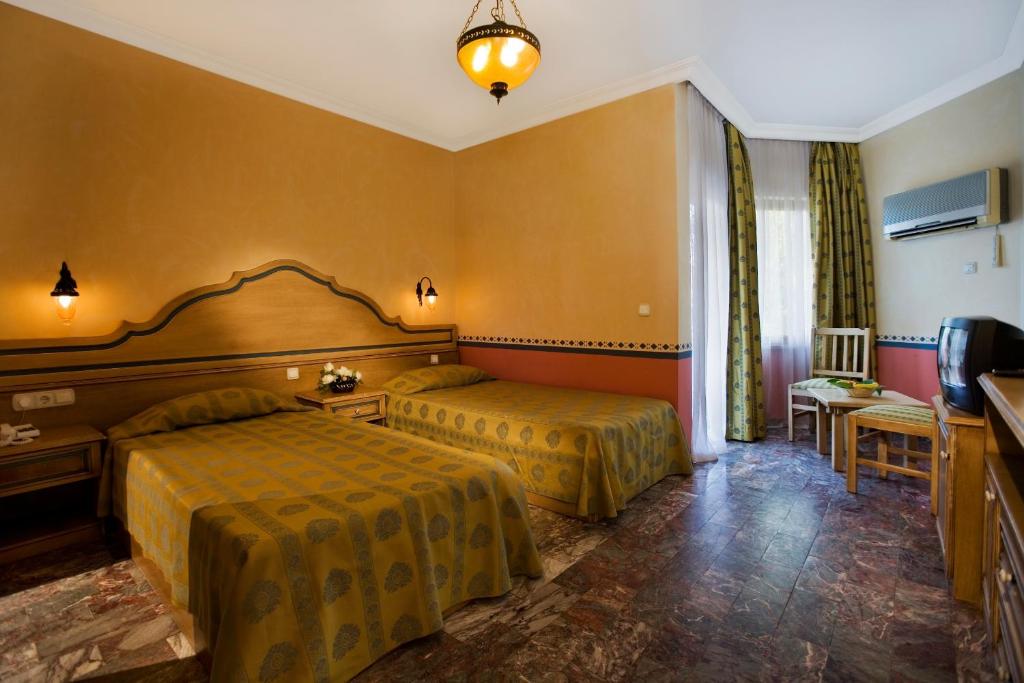 a hotel room with two beds and a television at Marvıda Hotel Akman Park in Kemer