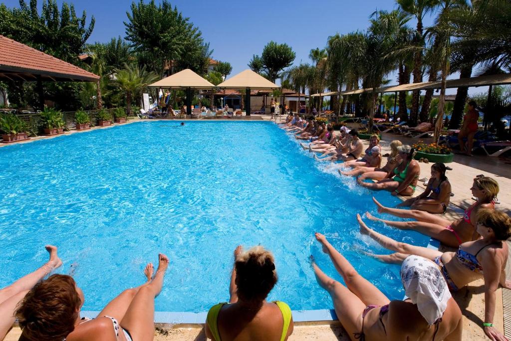 a group of people sitting around a swimming pool at Marvıda Hotel Akman Park in Kemer