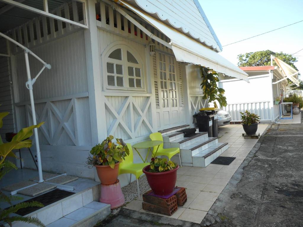 un porche de una casa con sillas verdes y plantas en Appartement Vue Jardin Fleuri, en Le Lamentin