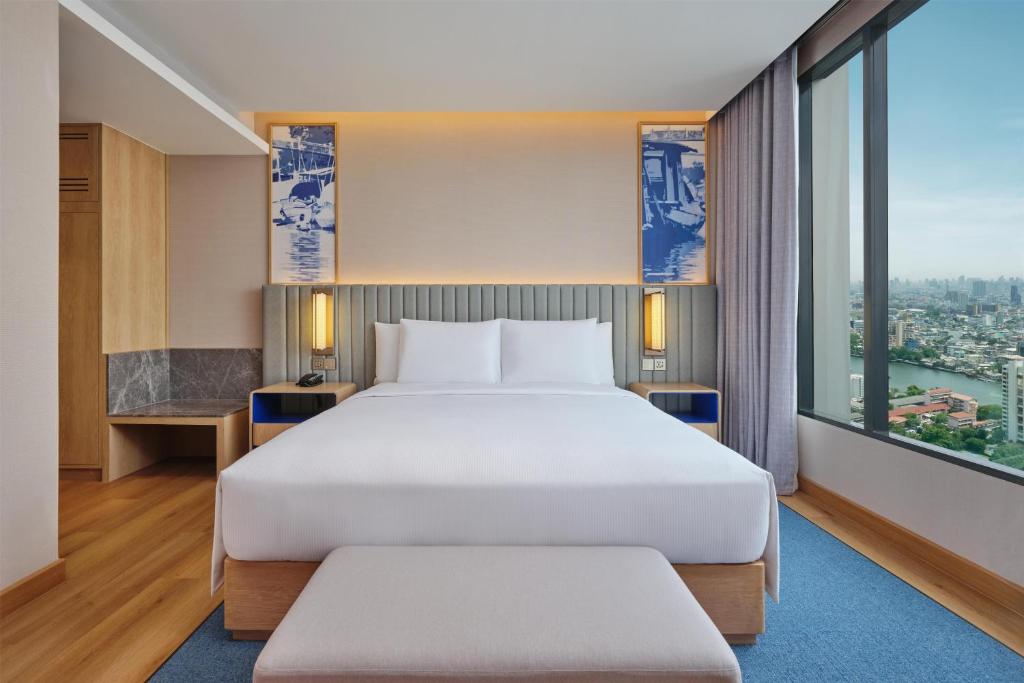 A king-bed room with a floor-to-ceiling window overlooking the river and city.