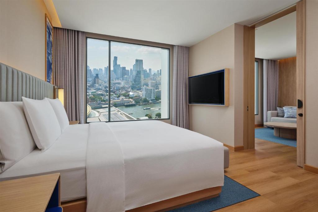 A king bedroom with a river-and-skyline view and a wall-mounted television.
