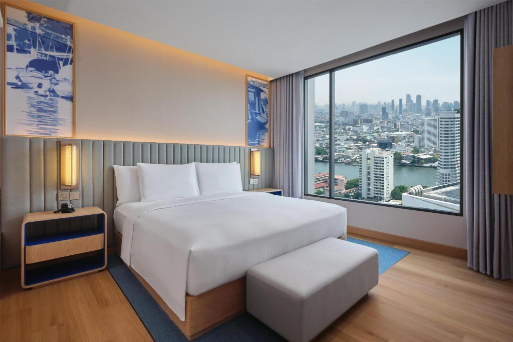 A king bedroom with a large river-and-skyline window and an upholstered bench.