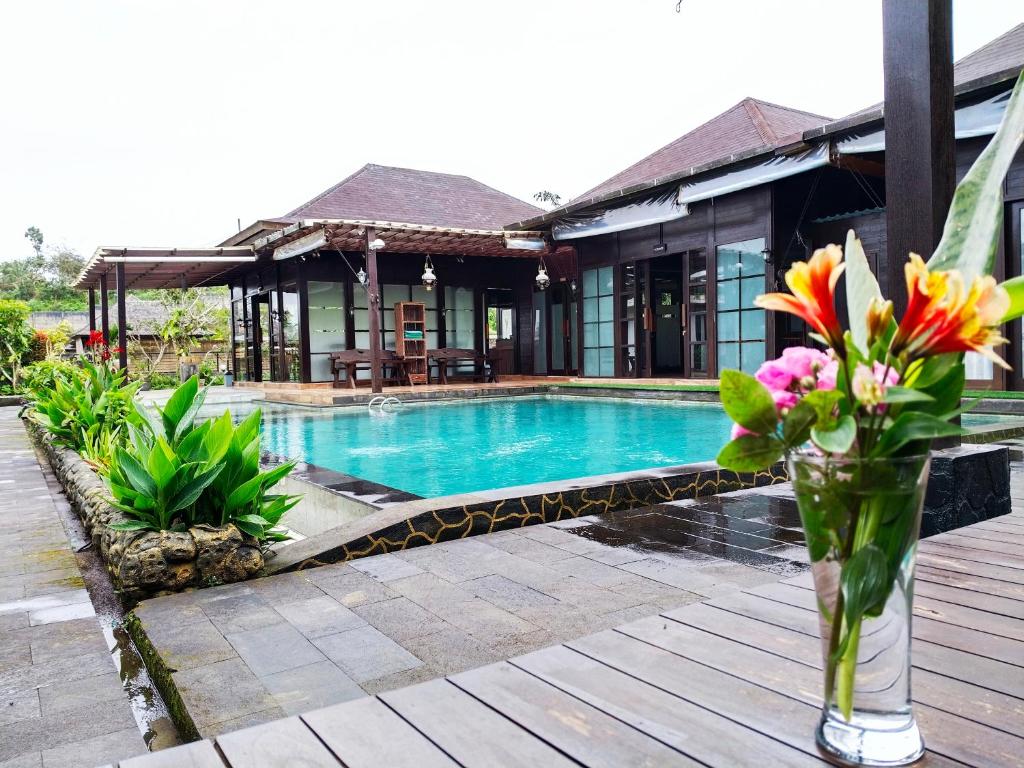a vase of flowers sitting on a deck next to a swimming pool at Merlyn Meadows Retreat in Munduk
