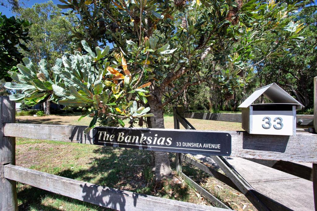 a sign on a fence in front of a tree at The Banksia's in Tea Gardens