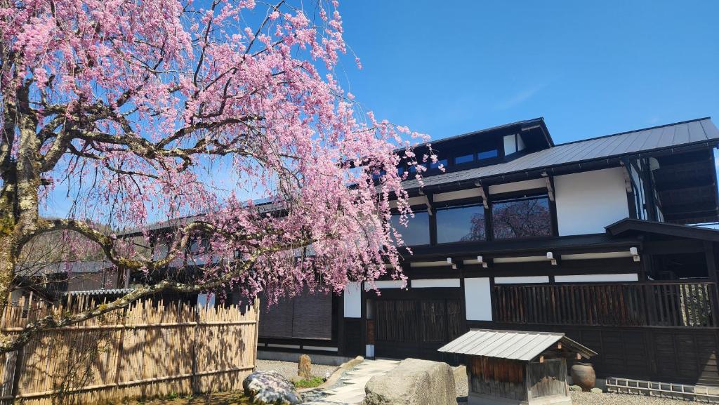 a house with a flowering tree in front of it at Onsen and Garden Nana in Kanazawa