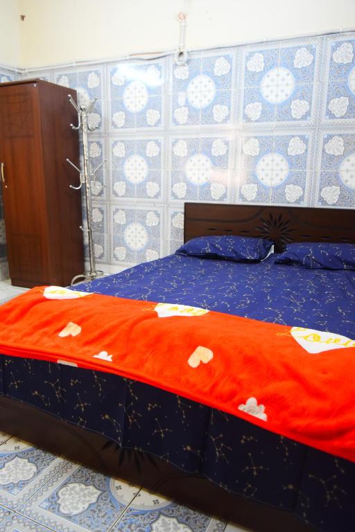a bed with an orange blanket with hearts on it at Kompass - Home Stay in Dhaka