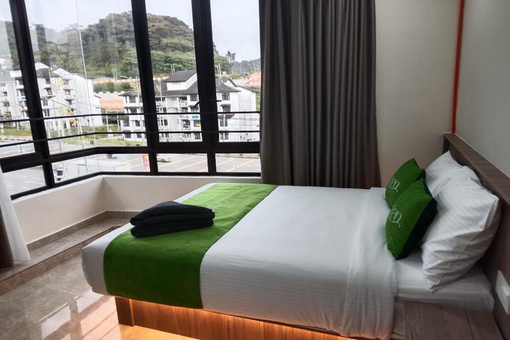 a bed in a room with a large window at Cameron Green Inn Hotel in Brinchang
