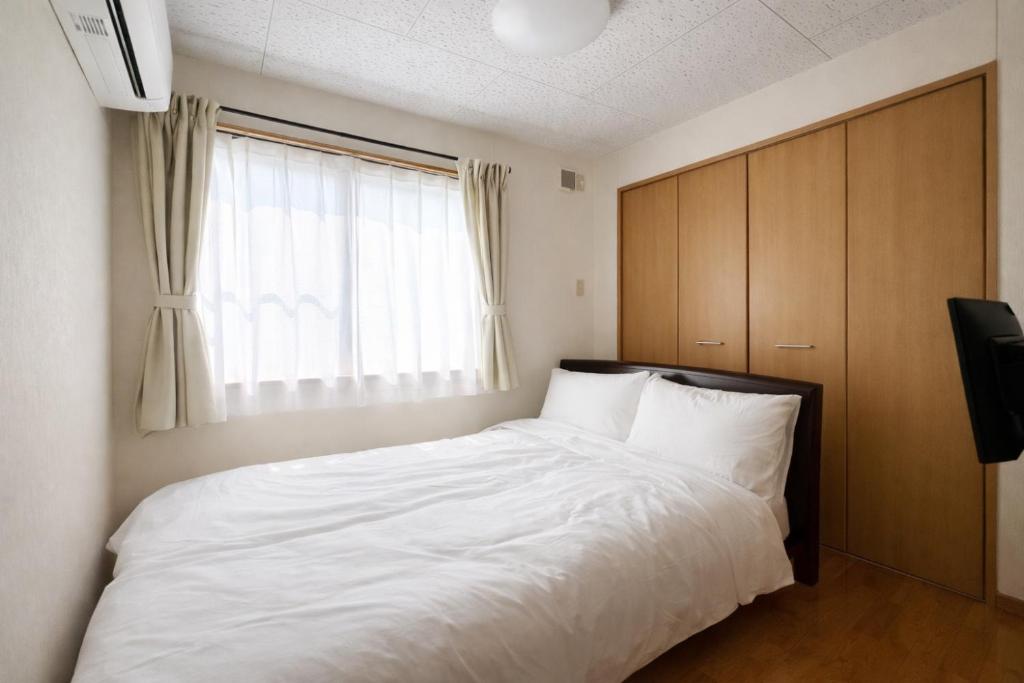 ein Schlafzimmer mit einem Bett mit weißer Bettwäsche und einem Fenster in der Unterkunft Little House Private House in Yakushima