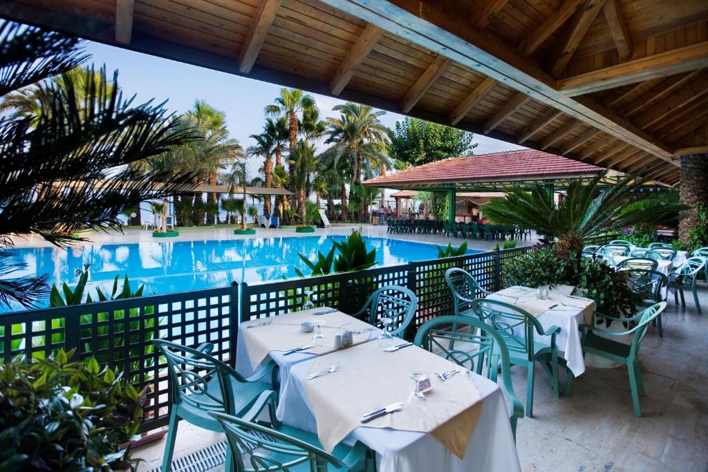 a restaurant with tables and chairs next to a pool at Marvıda Hotel Akman Park in Kemer