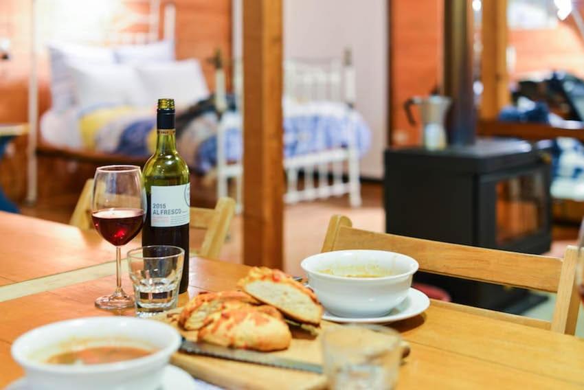 a table with a bottle of wine and a plate of food at Georgina's place, Kangaroo Island in Brown Beach