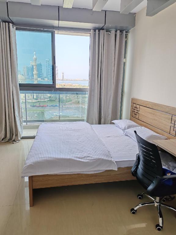 a bedroom with a bed and a desk and a window at King bed sea view in Sharjah