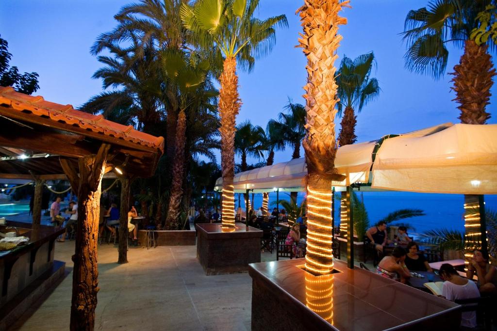 a restaurant with palm trees and people sitting at tables at Marvıda Hotel Akman Park in Kemer