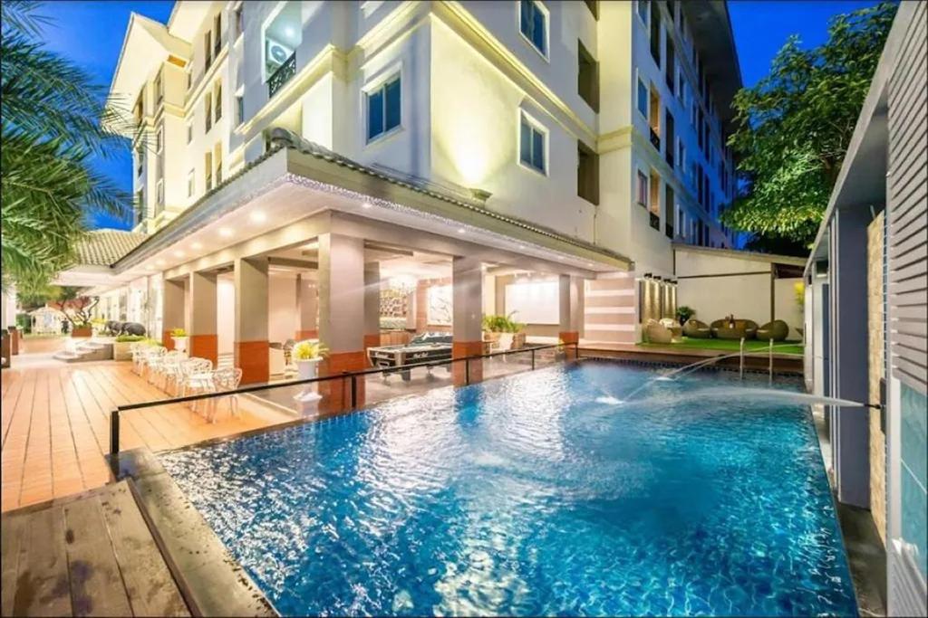 a swimming pool in front of a building at Napheera Royal Tel in Ban Khlong Bang Krathiam