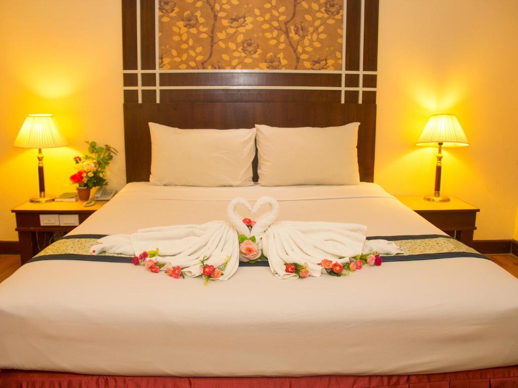 a bedroom with a bed with two robes at Friendlytel Hotel in Hat Yai