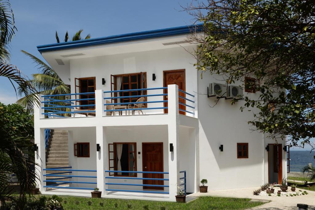 a white house with a blue balcony at Villa in Blue in Dauin