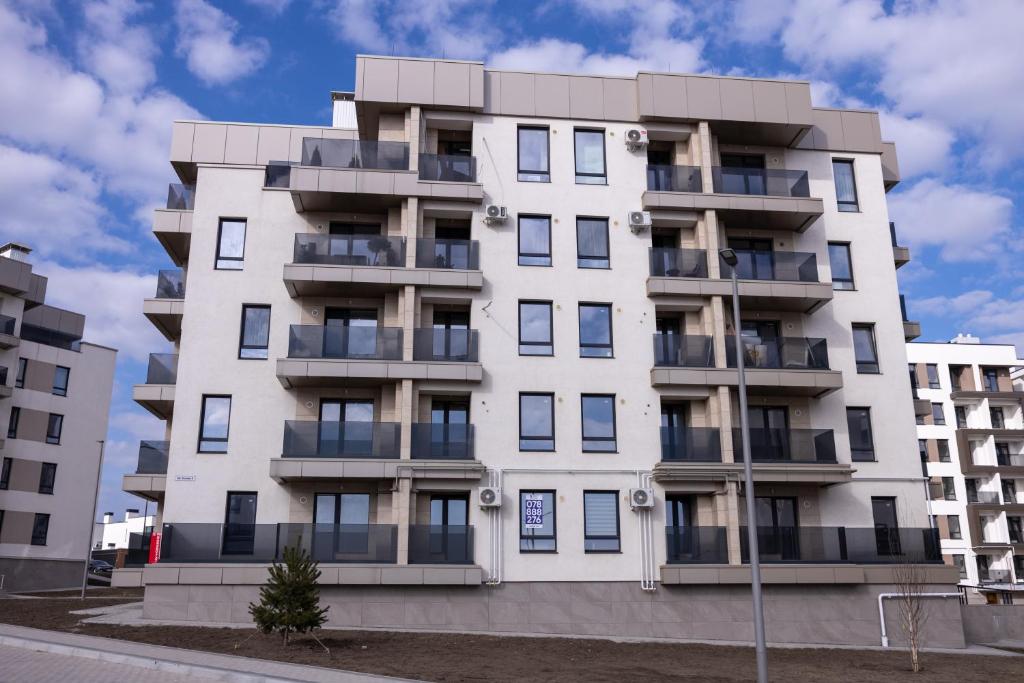 a white building with balconies on a street at Apartaments Parking Taxi in Chişinău