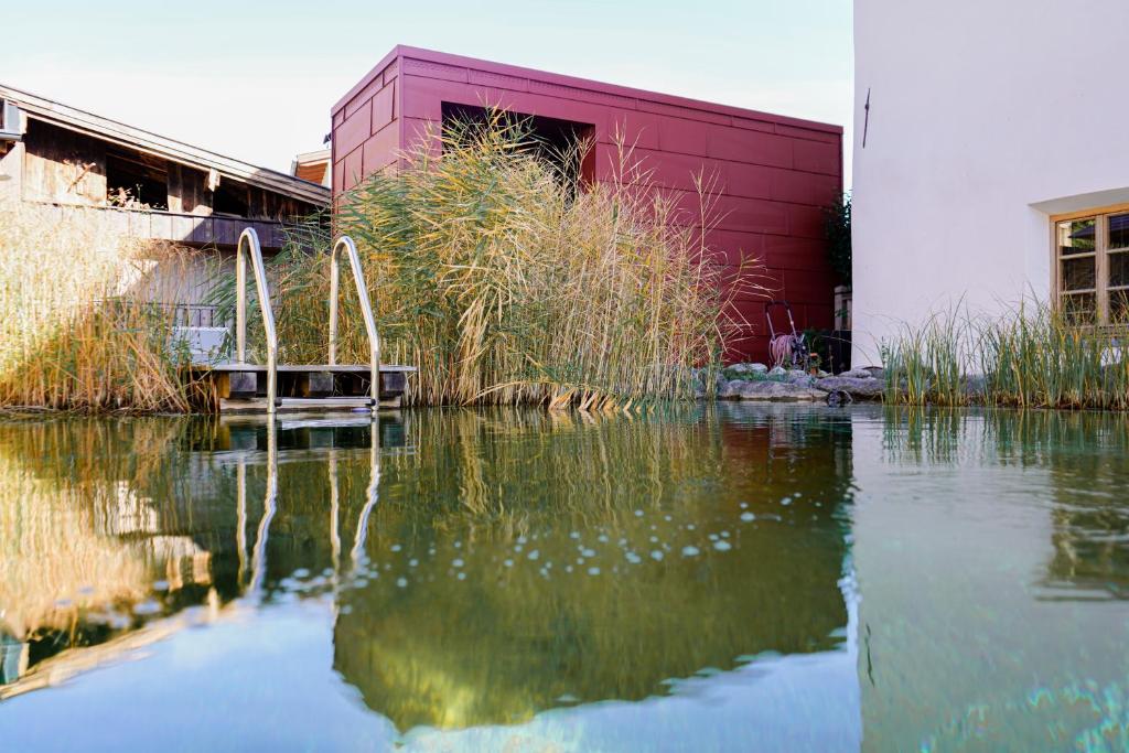 a body of water in front of a red building at Edelnest by Peak Stay in Stans