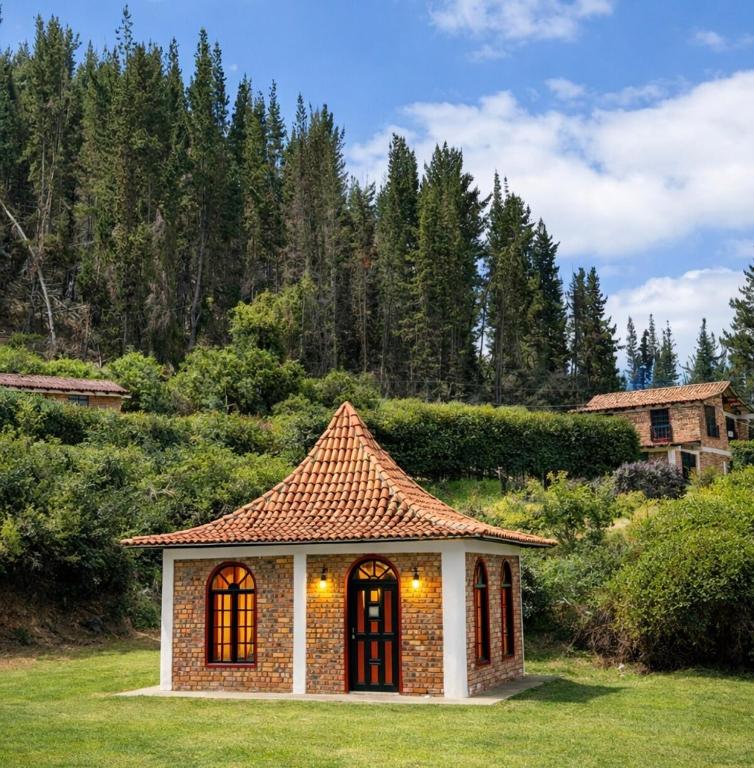 a small house with a tiled roof in a yard at La Casita de Carpintero in Cucunubá