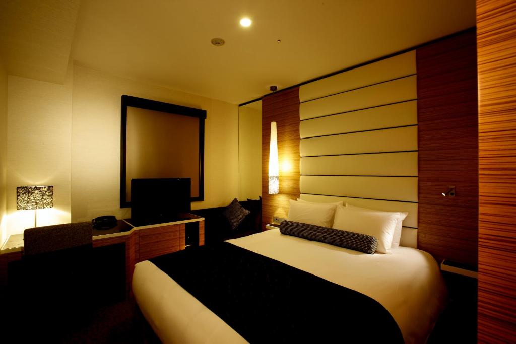 a hotel room with a bed and a desk and a television at Hotel Trusty Osaka Abeno in Osaka