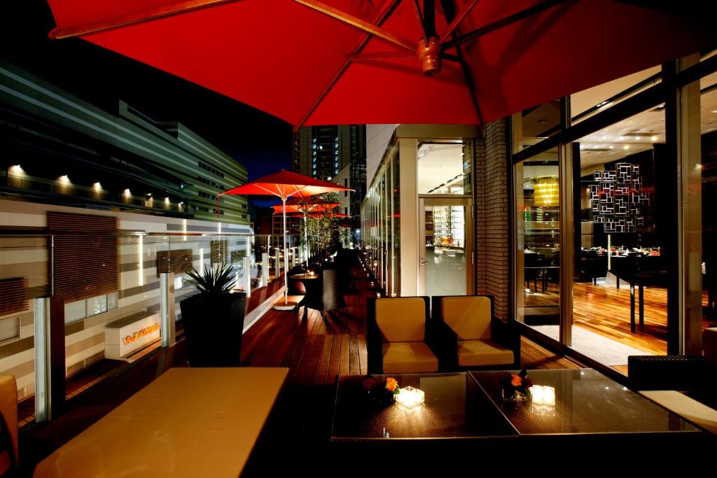 a restaurant with a red umbrella and a table and chairs at Hotel Trusty Osaka Abeno in Osaka