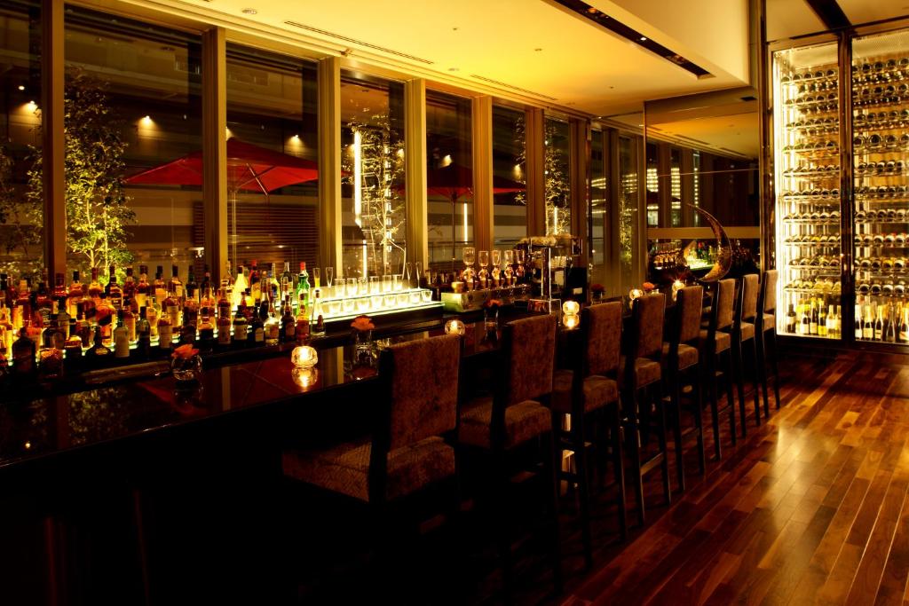 a bar with chairs in a room with wine bottles at Hotel Trusty Osaka Abeno in Osaka
