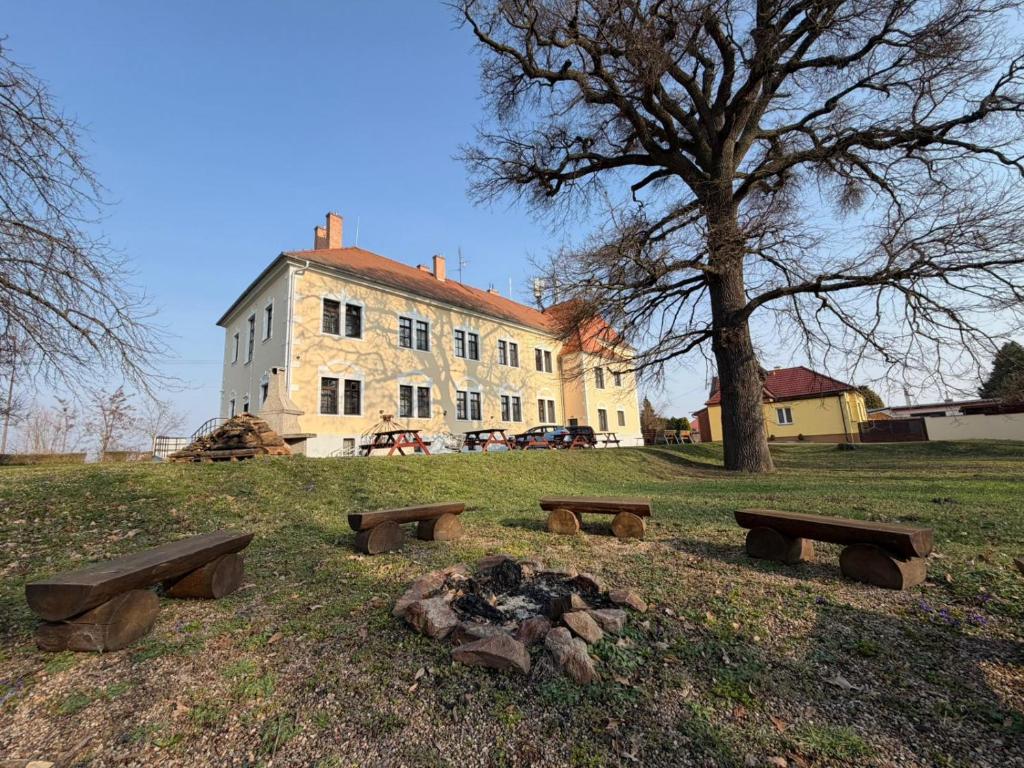 a building with benches and a campfire in a field at Koleje Zámeček in Lednice