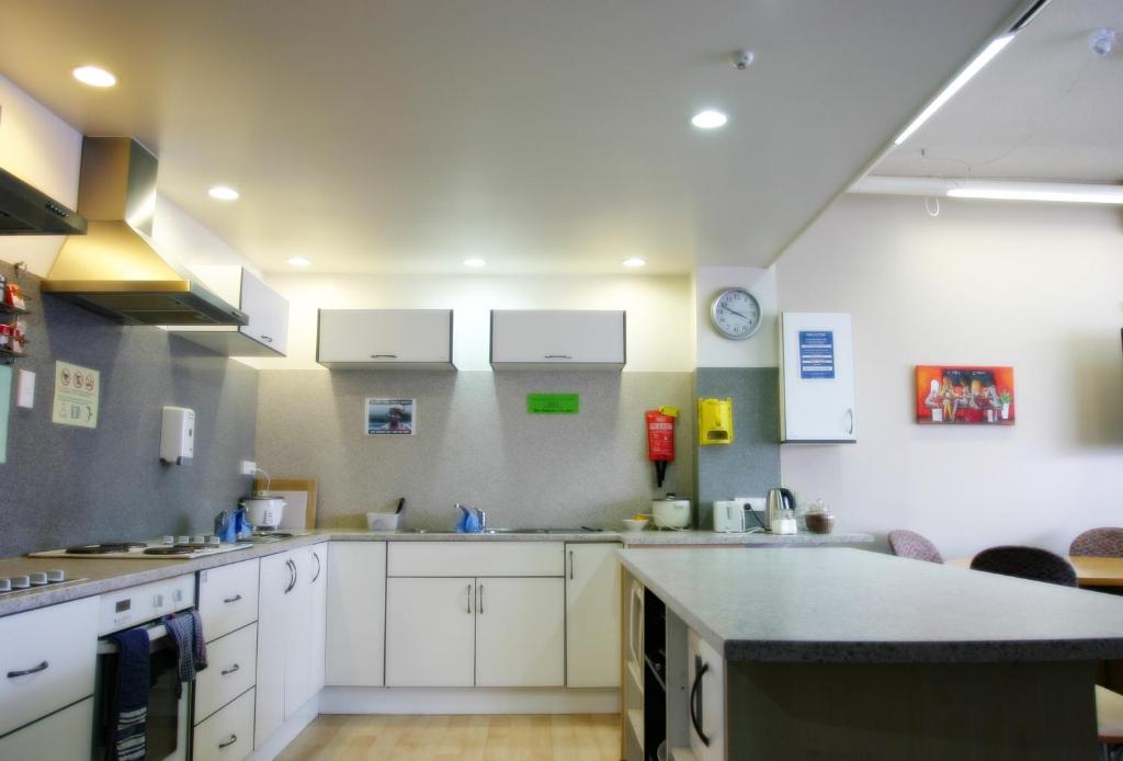 a large kitchen with white cabinets and a counter at Backpackers Central Hamilton in Hamilton