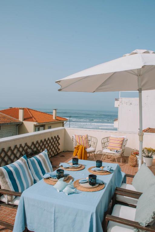 a table with chairs and an umbrella and the beach at Casas dos Seixos in Moledo
