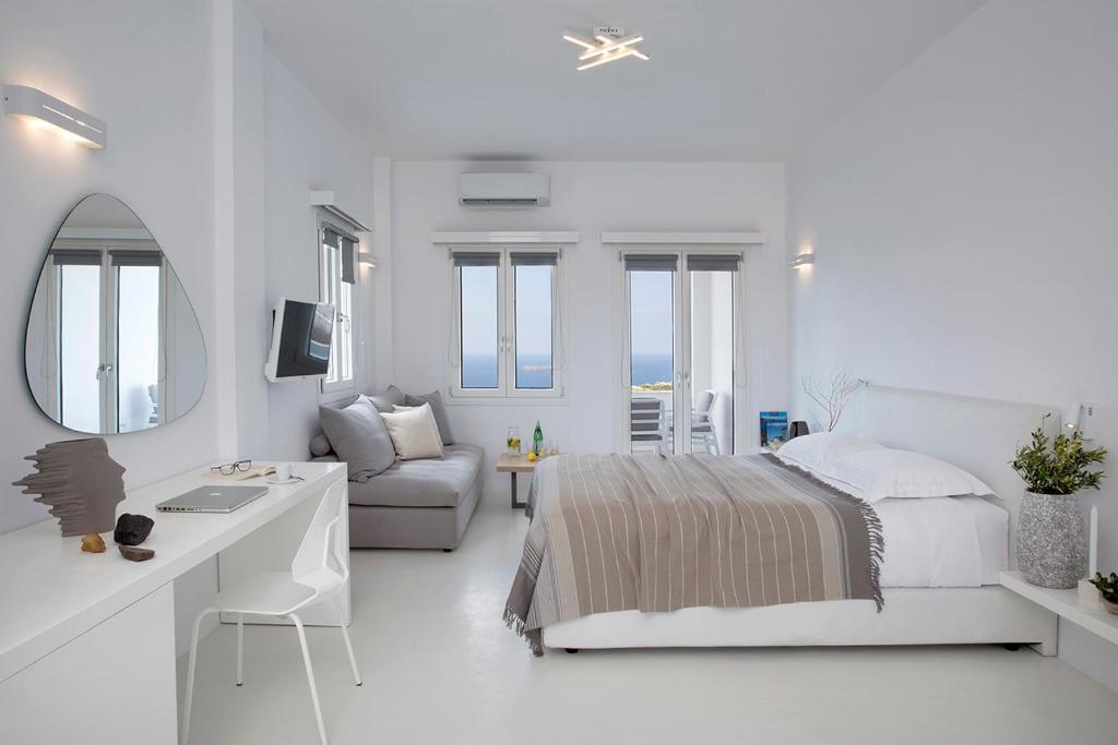 a white bedroom with a bed and a desk at Blue Vice Megalochori in Megalochori