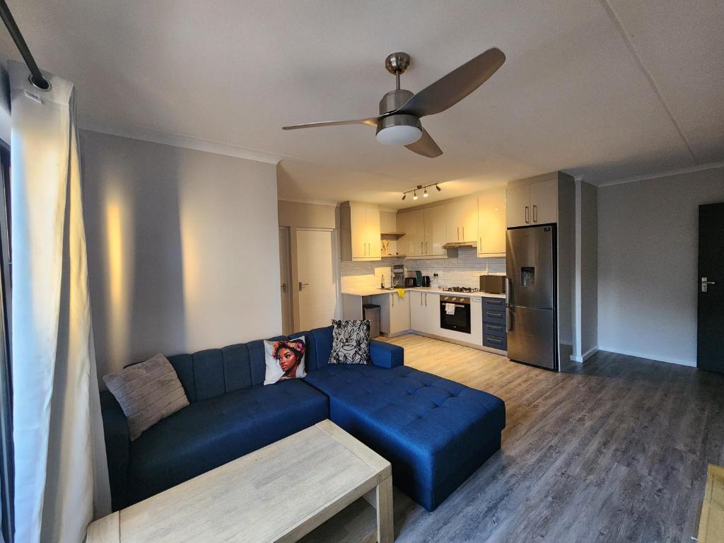 a living room with a blue couch and a kitchen at Manchester Heights in Cape Town