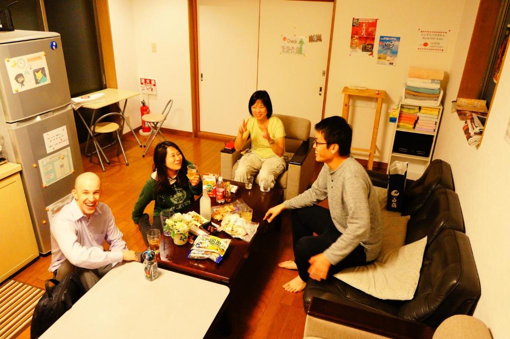 a group of people sitting around a table in a room at Osaka Tomato Guesthouse in Osaka