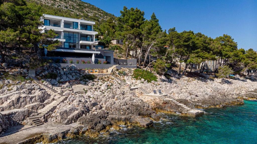 a house on a rocky hill next to the water at Luxury Seafront Villa Miracul Korcula with Pool in Blato