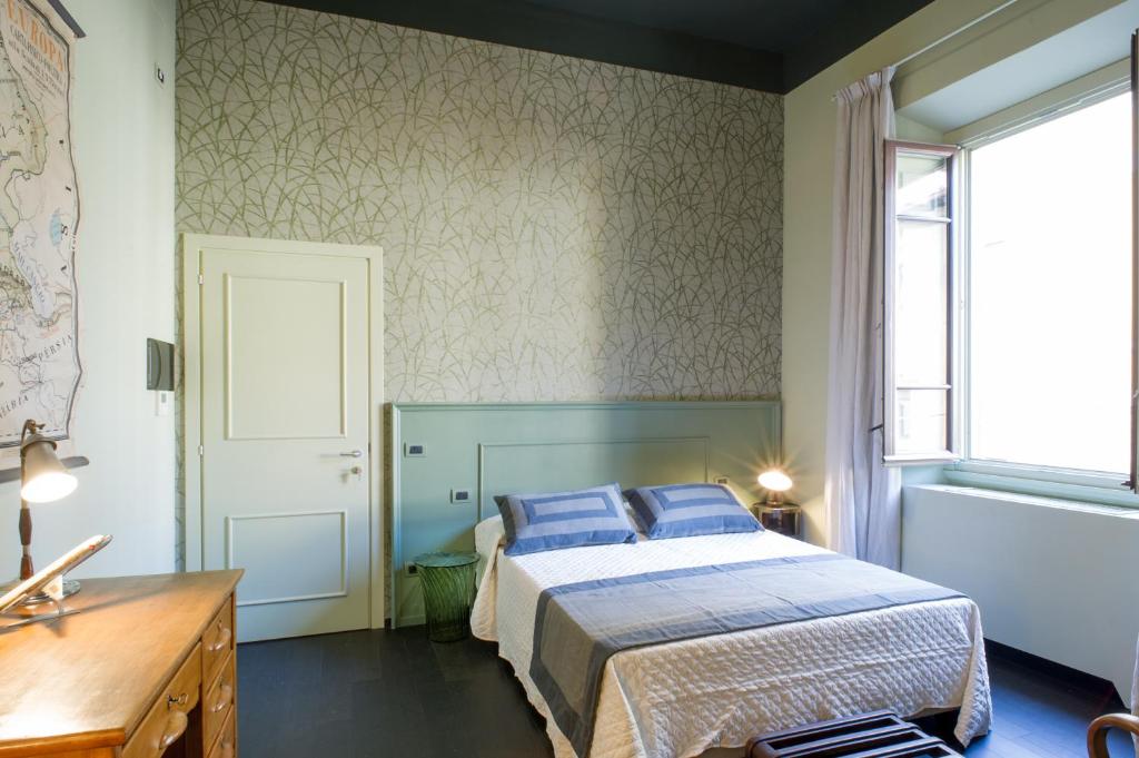 una camera da letto con un letto con cuscini blu e una finestra di Arnobio Florence Suites a Firenze
