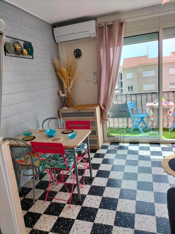 a kitchen with a table and chairs on a checkered floor at studio centre plage in Canet-en-Roussillon