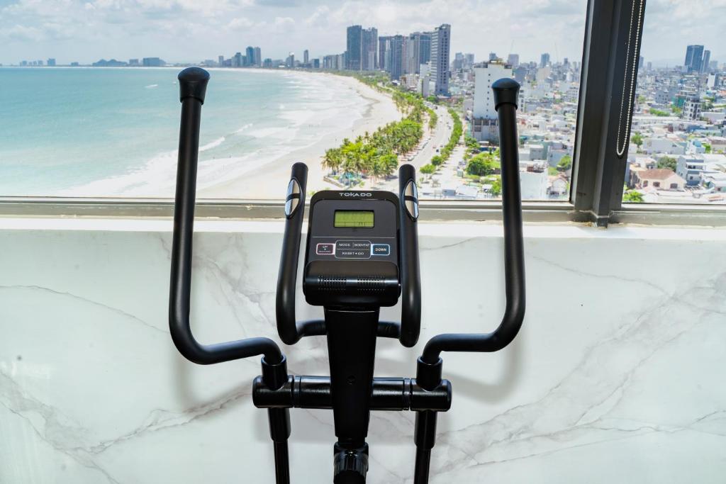 An exercise bike is positioned directly in front of a high-rise beach panorama.