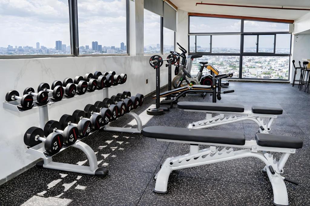 A bright, window-lined fitness room combines dumbbells, benches and cardio equipment.