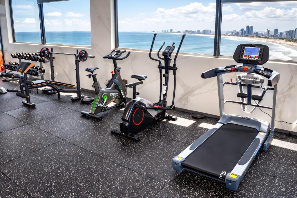 Cardio equipment is lined up beside windows facing the beach and skyline.