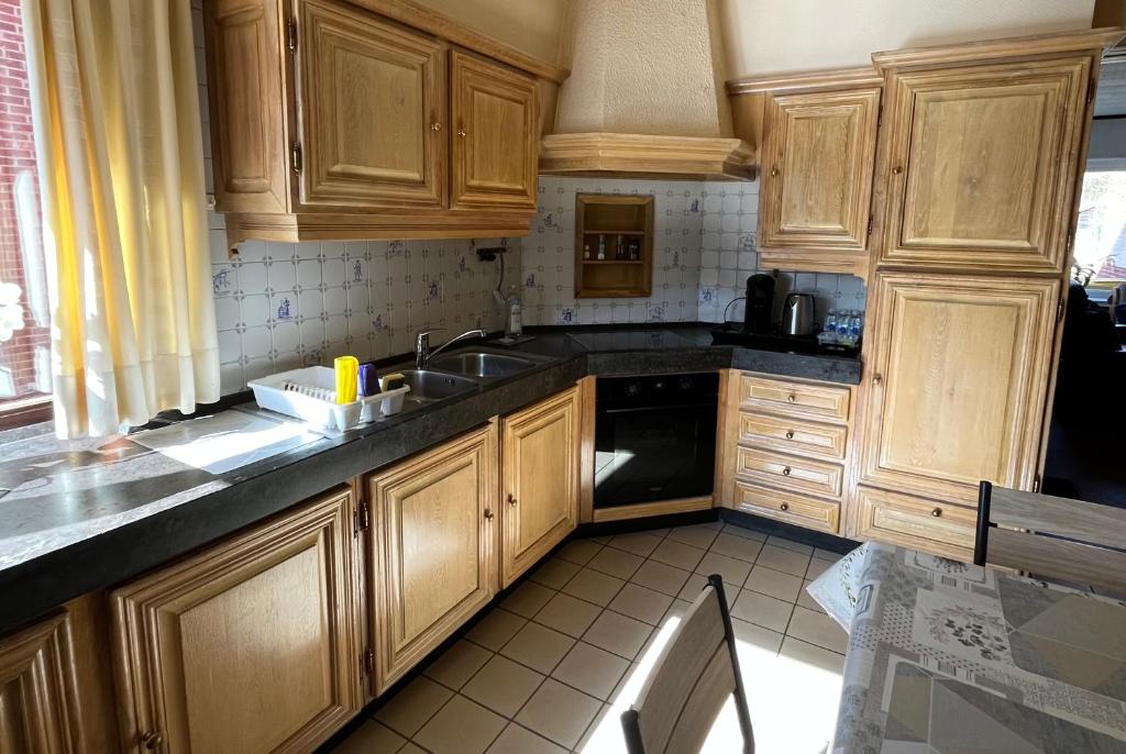 a kitchen with wooden cabinets and a sink at Vakantiehuis Santorini in Westerlo