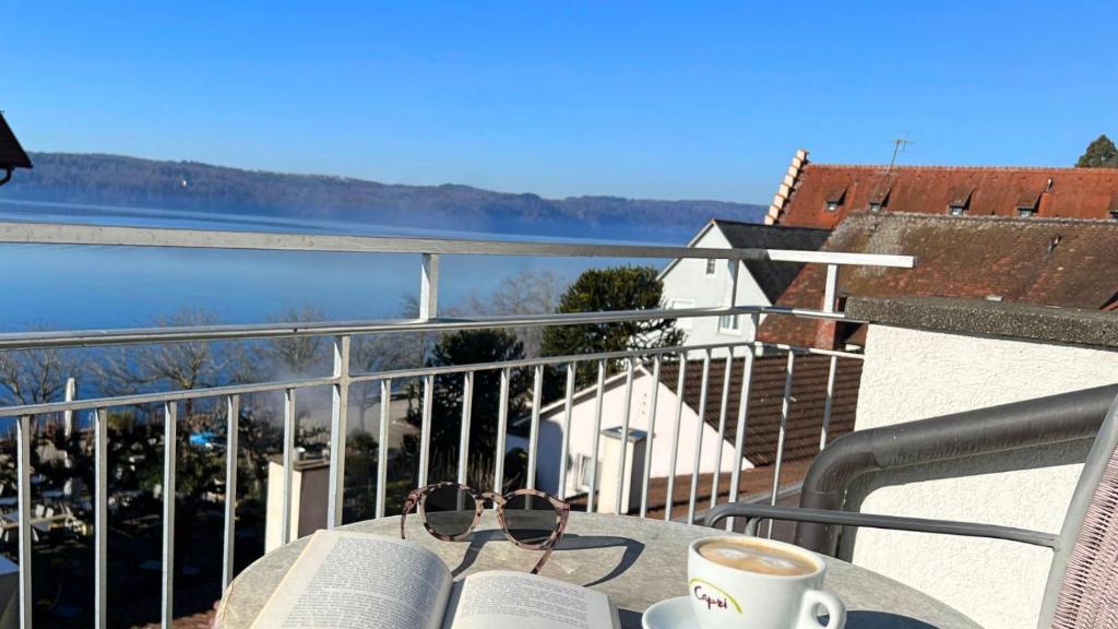 a table with a cup of coffee and books on a balcony at Hotel Capri in Überlingen
