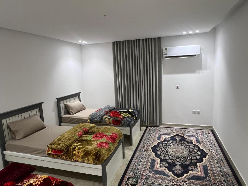 a room with two beds and a couch and a rug at شقق الشموخ in Dammam