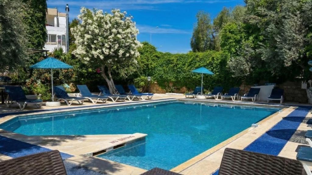 a swimming pool with chairs and umbrellas at Ali Baba Hotel Gümbet in Gümbet