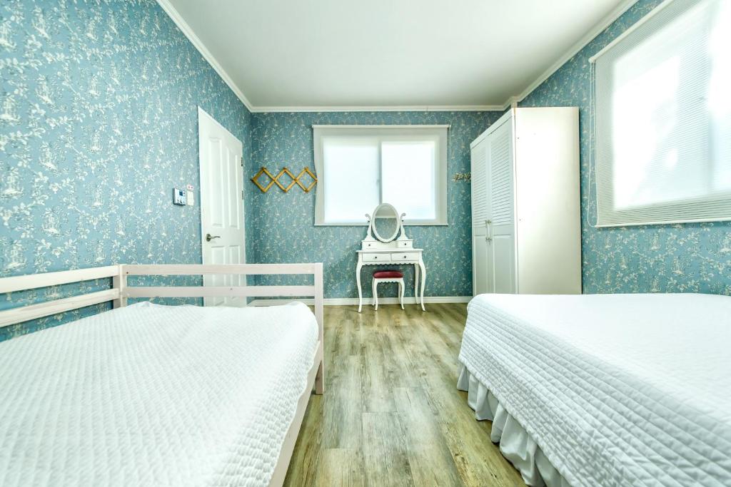 a blue bedroom with two beds and a desk at Mirvill Pension & Resort in Seogwipo