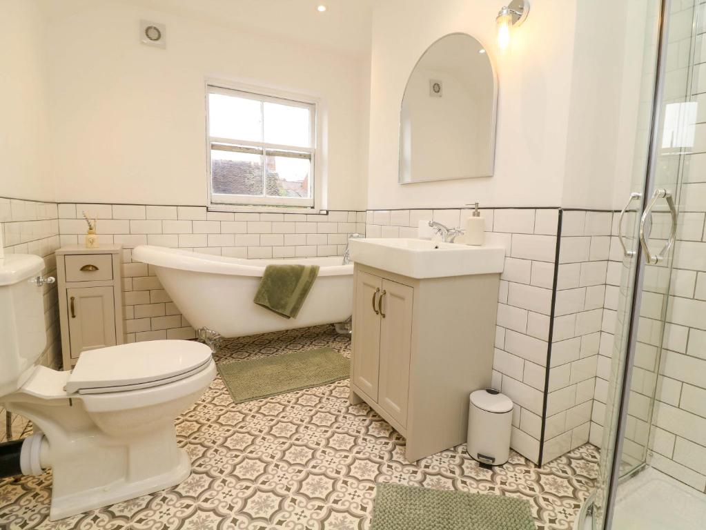 a bathroom with a toilet and a tub and a sink at Crown Cottage in Belper