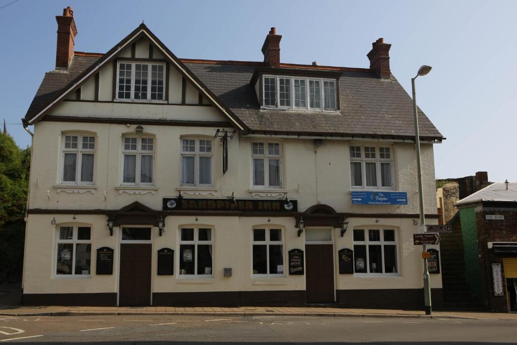 a white building on the corner of a street at Sandpiper Inn B&B and Pub in Ilfracombe