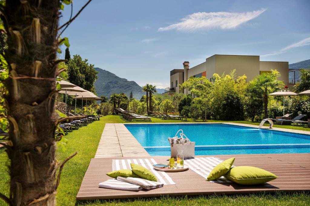 a pool with a table and pillows next to a resort at Active & Family Hotel Gioiosa in Riva del Garda