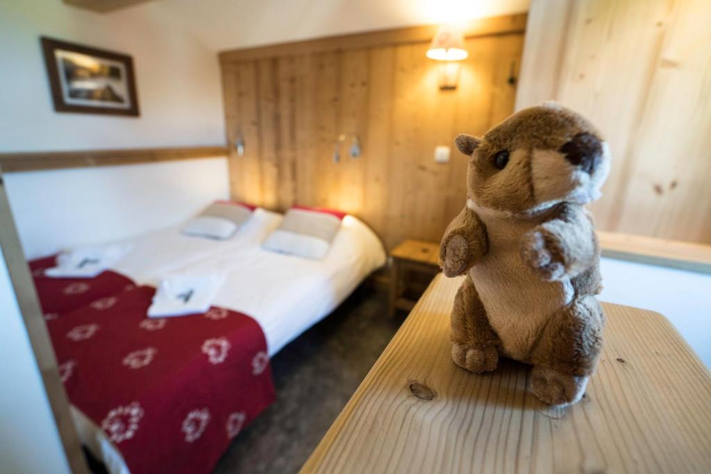 Un ours en peluche assis sur une table dans une chambre d'hôtel dans l'établissement Village De Vacances Les Flocons Verts, aux Carroz d'Arâches