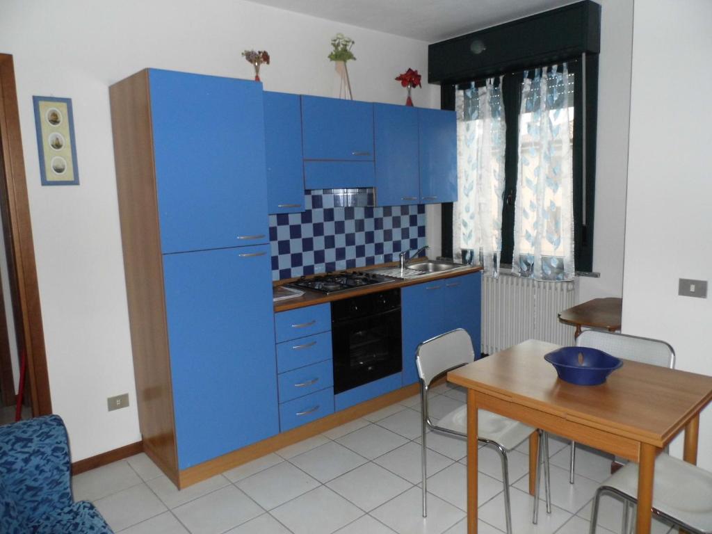 帕爾馬的住宿－Bilocale Mentana 21，厨房配有蓝色橱柜、桌子和用餐室。