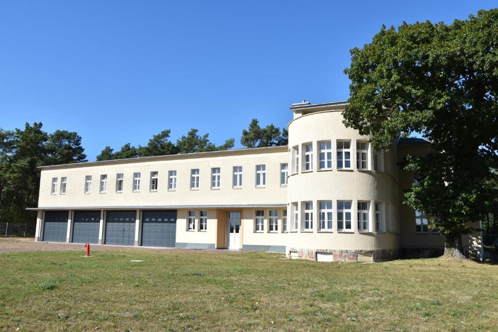 a large white building with a tree in front of it at Pension Alte Flugleitung in Stendal