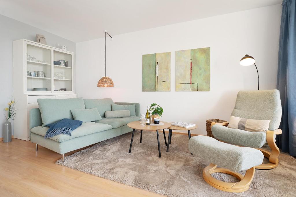 a living room with a blue couch and two chairs at Waldstraße 2 Windrose Kellenhusen in Kellenhusen