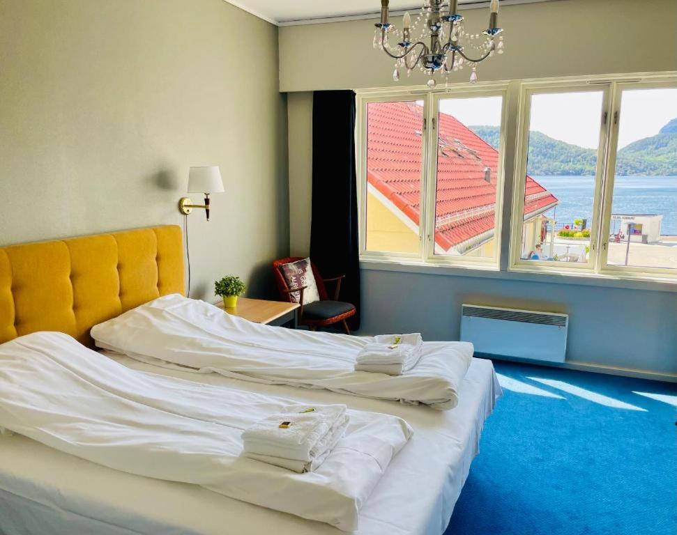 two beds in a room with a large window at Lindum Hotell in Bergjord